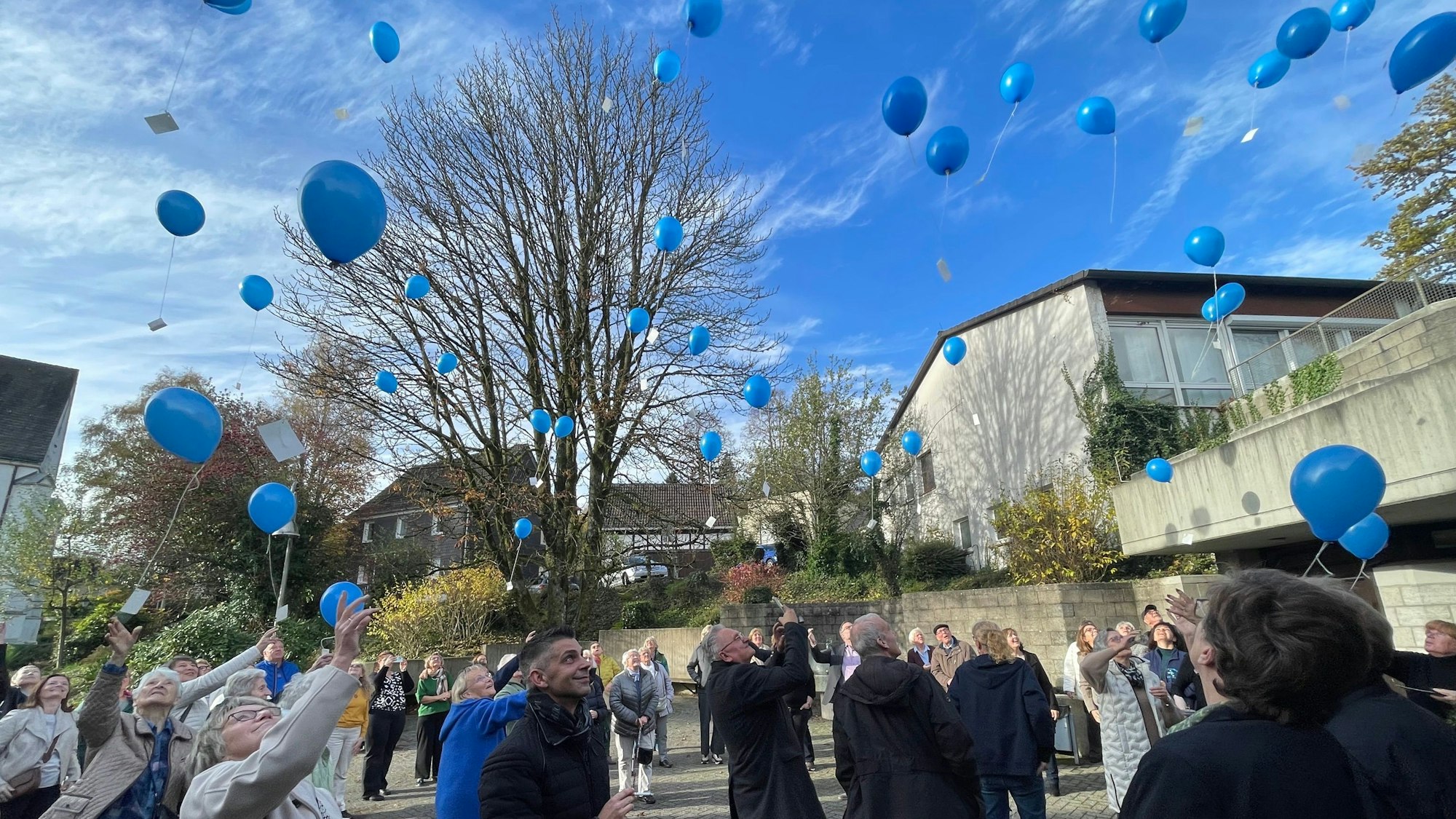 Beteiligte lassen blaue Ballons steigen.