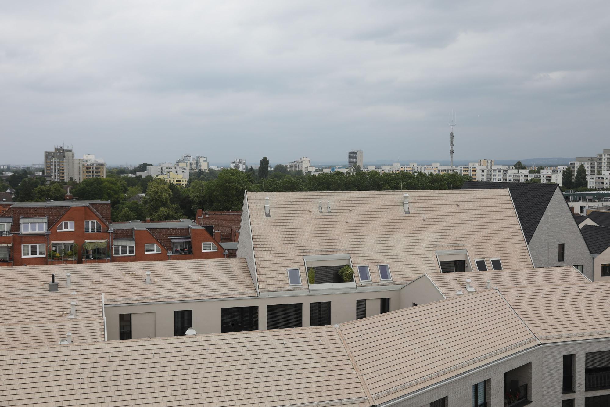 Im Vordergrund sind die Dächer der Neubauten in Porz Mitte zu sehen, im Hintergrund die Hochhaussiedlung in Finkenberg.