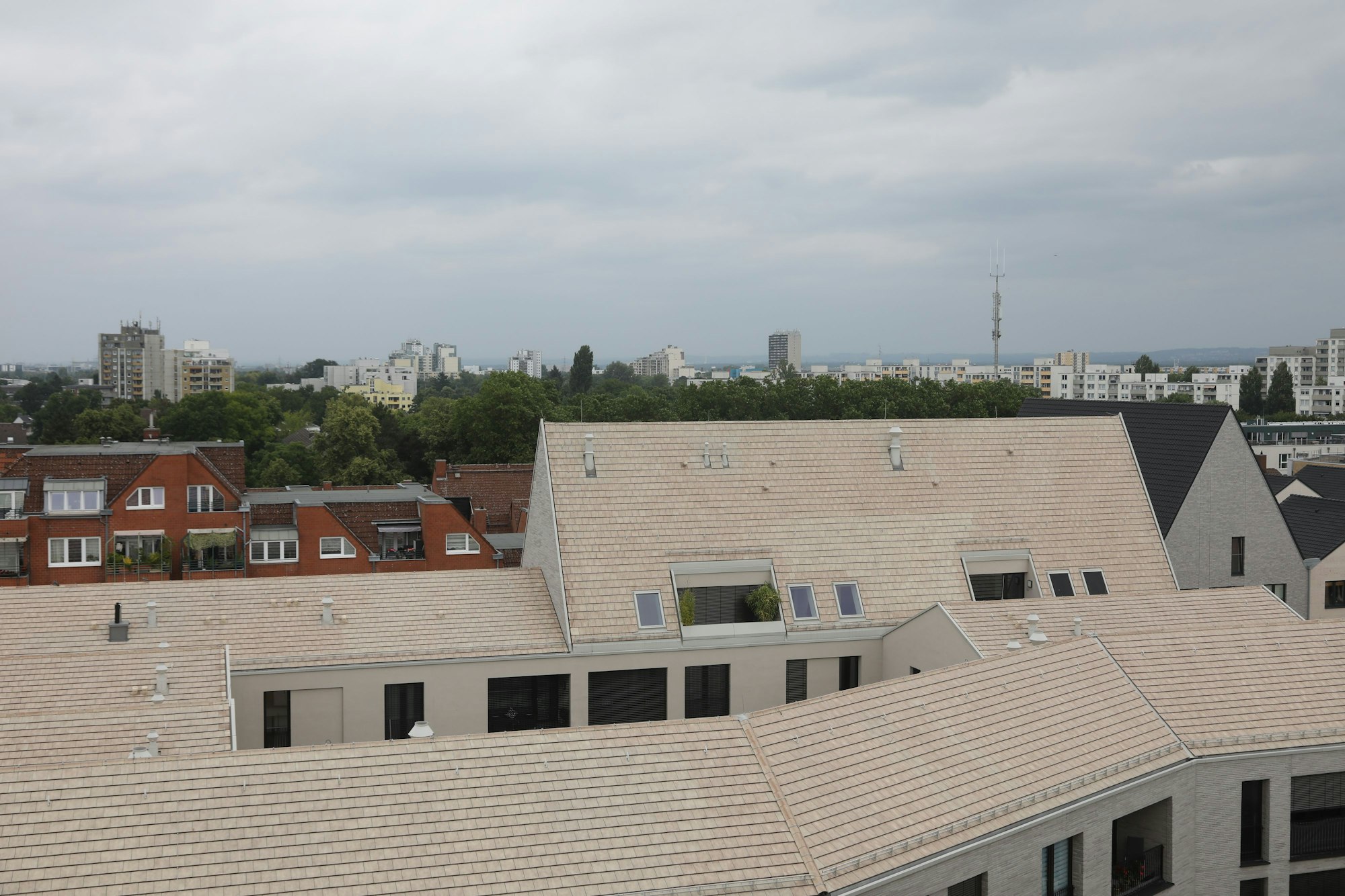 Im Vordergrund sind die Dächer der Neubauten in Porz Mitte zu sehen, im Hintergrund die Hochhaussiedlung in Finkenberg.