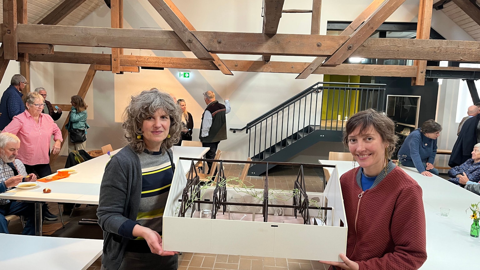 Zwei Frauen halten das Modell eines ausgebauten Dachbodens.