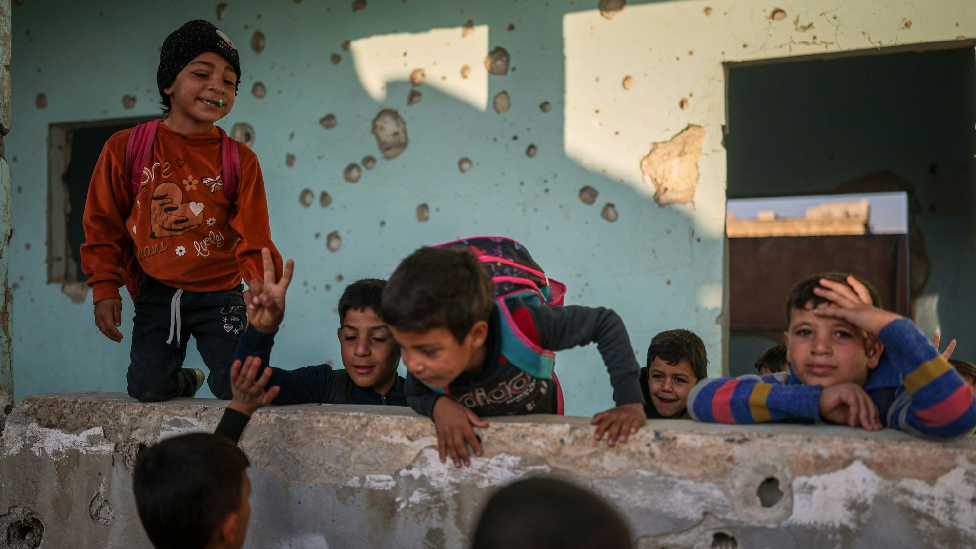 Schüler spielen im Hof der Grundschule im Dorf Maar Schmarin in der Region Idlib. Die Wände der Schule sind von Einschusslöchern übersät.