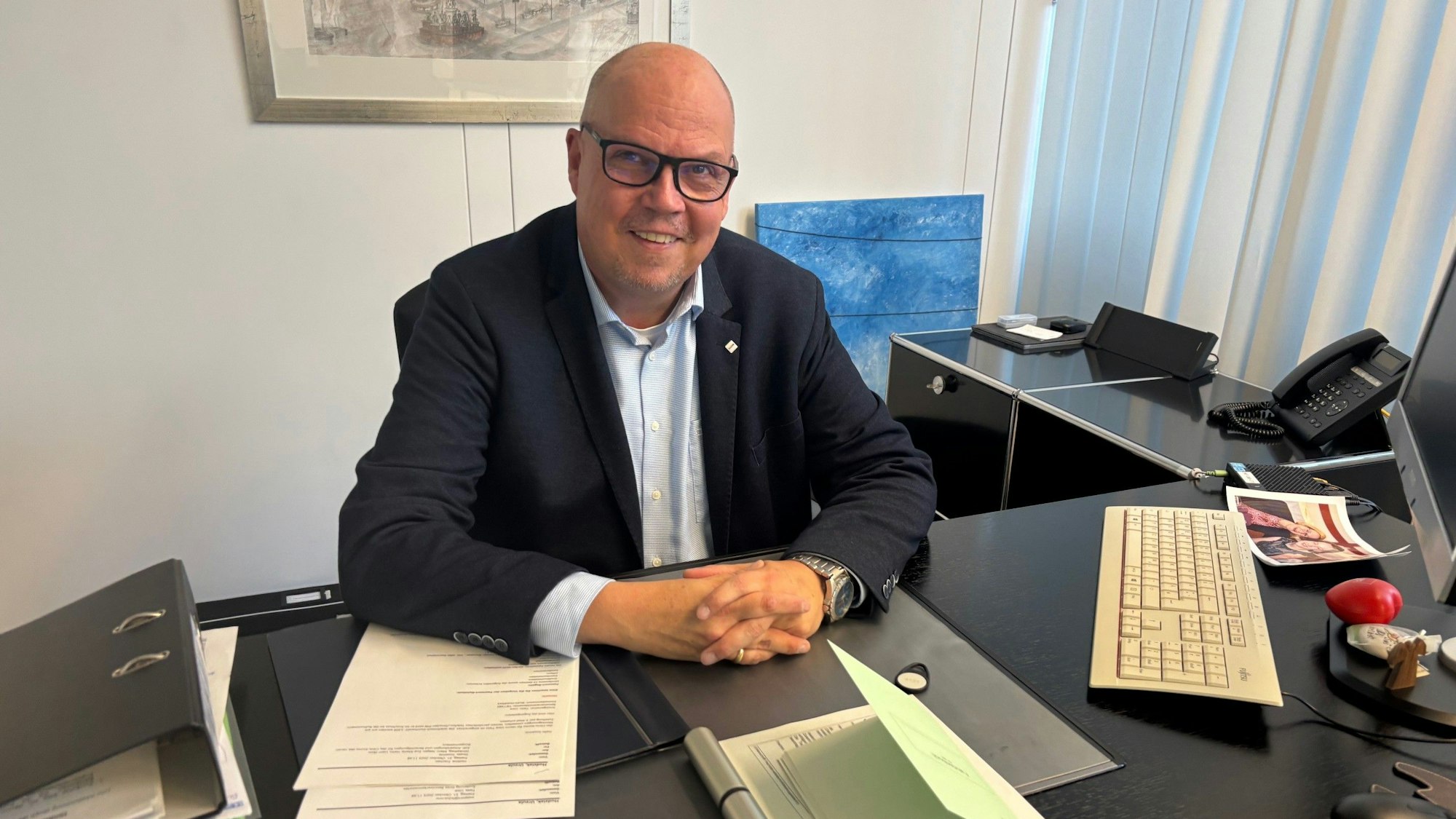 Auf dem Bild ist ein Mann an einem Schreibtisch zu sehen.