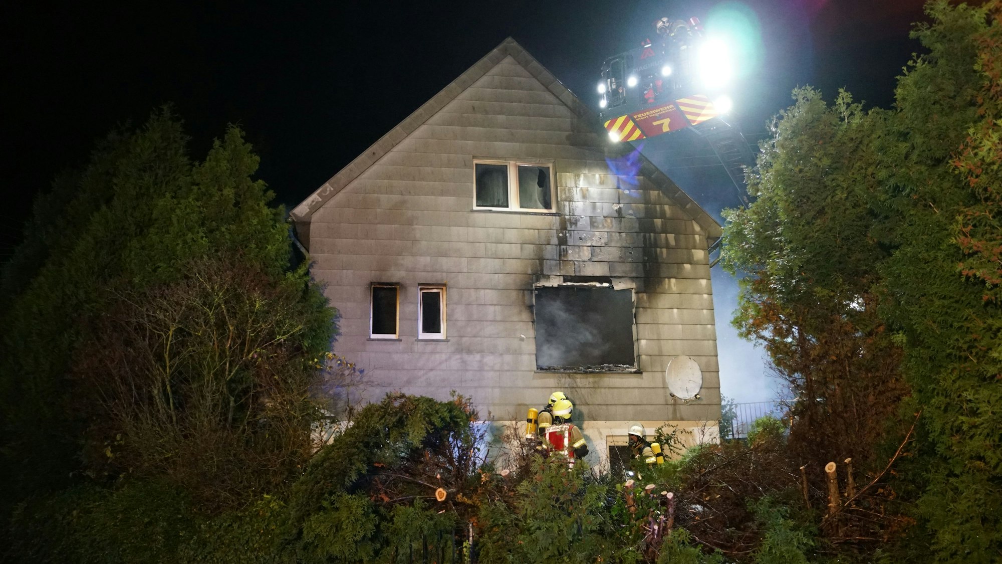 Feuerwehrleute stehen an einem Haus in Mechernich, das ausgebrannt ist.