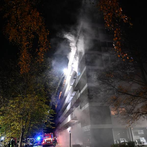 Rauchwolken kommen aus einem Mehrfamilienhaus.