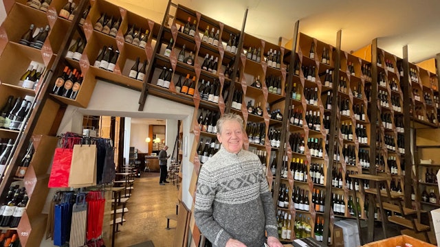 Ein Mann steht in einem großen Raum, an dessen Wand zahlreiche Weinregale nebeneinander stehen.