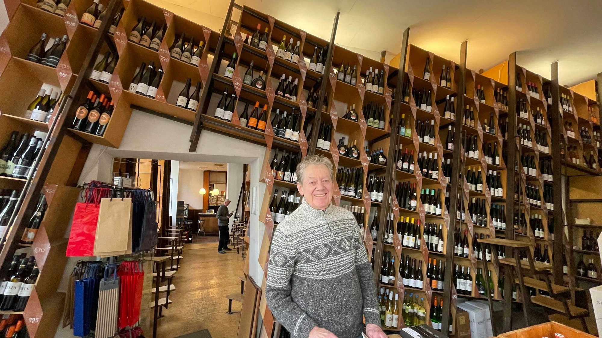 Ein Mann steht in einem großen Raum, an dessen Wand zahlreiche Weinregale nebeneinander stehen.