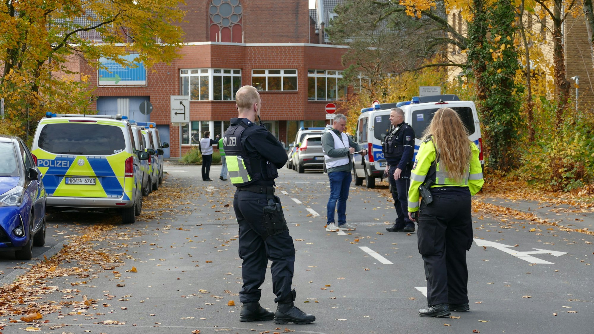 Polizistinnen und Polizisten stehen in der Zufahrt der JVA an der Luisenstraße in Siegburg.