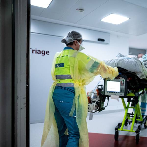Sanitäter schieben einen Patienten auf einer Trage durch ein Krankenhaus.