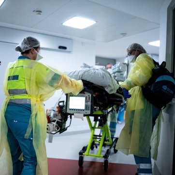 Sanitäter schieben einen Patienten auf einer Trage durch ein Krankenhaus.