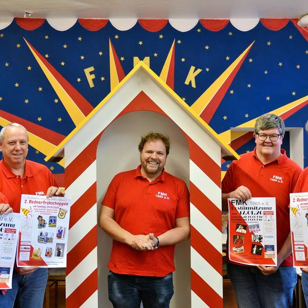 Männer in roten Poloshirts präsentieren Karnevals-Plakate. In der Mitte steht der zukünftige Prinz Torsten Krieg.