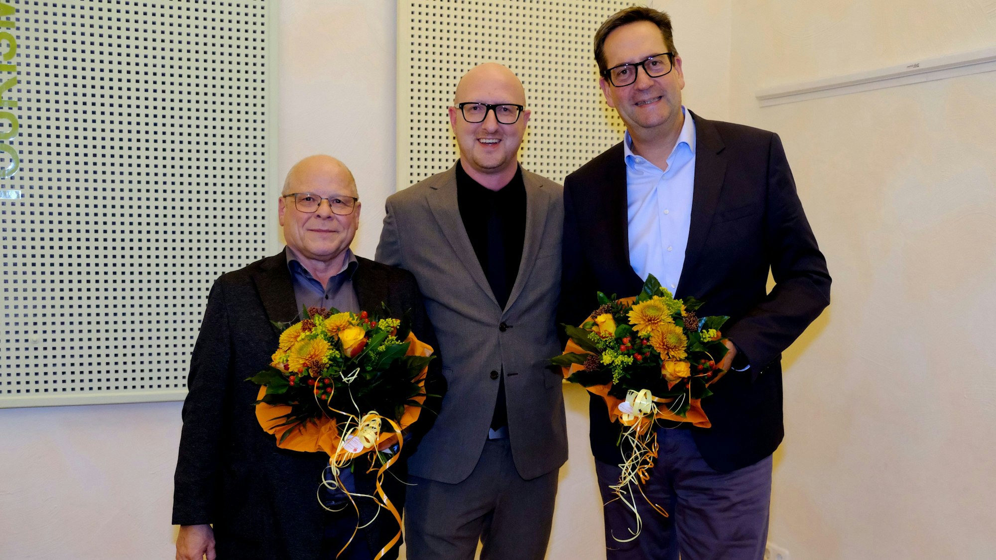 Bürgermeister Ingo Pfennings steht zwischen seinen Stellvertretern Gerd Wolter (l.) und Markus Herbrand, die jeweils einen Blumenstrauß in den Händen halten.