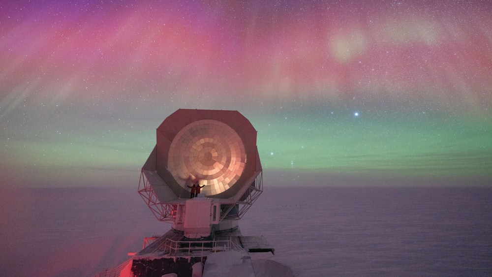 HANDOUT - Das Bild von Aman Chokshi zeigt ein riesiges Teleskop einer US-amerikanischen Forschungsstation am Südpol vor dem Hintergrund spektakulärer Polarlichter.