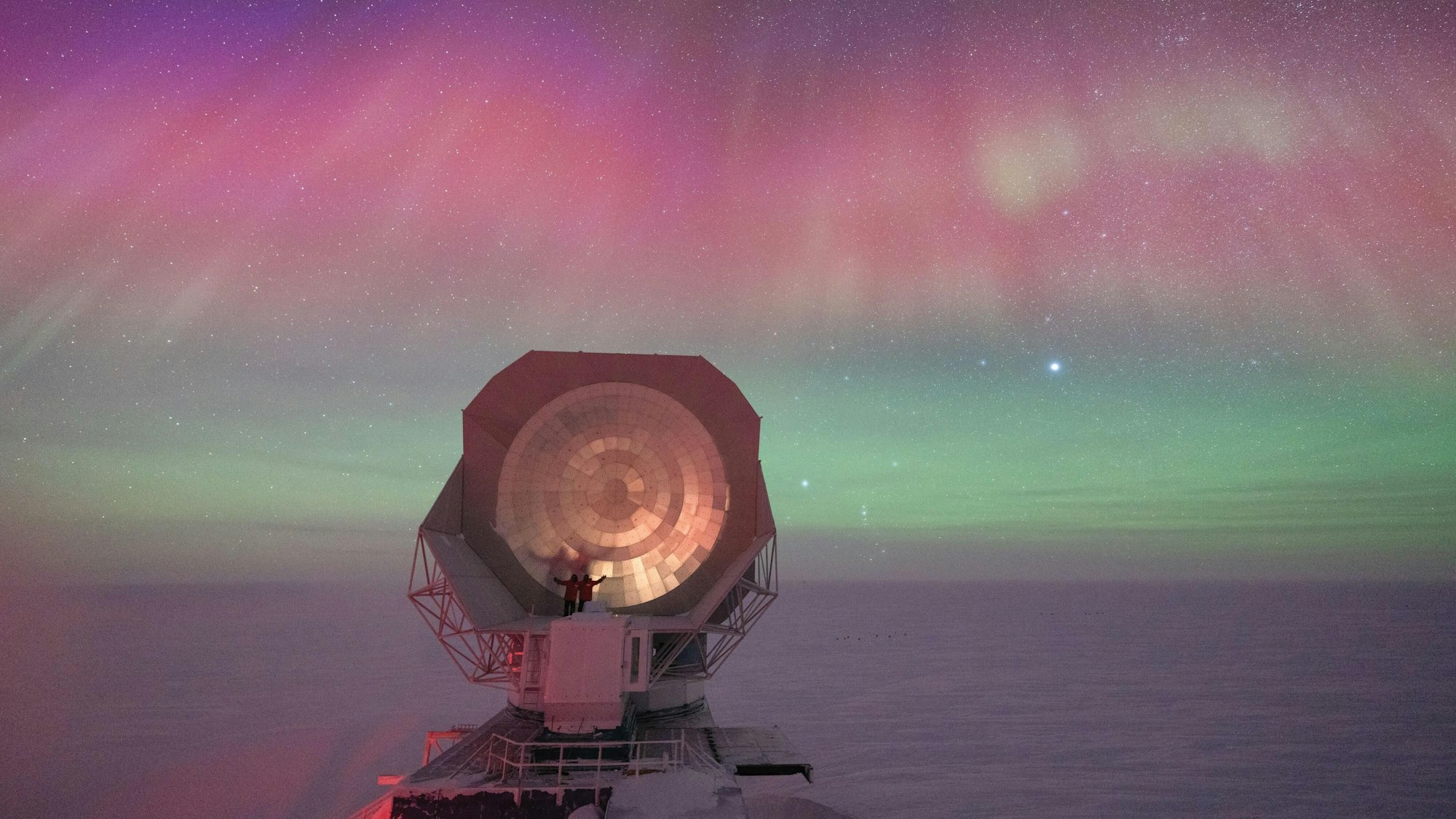 HANDOUT - Das Bild von Aman Chokshi zeigt ein riesiges Teleskop einer US-amerikanischen Forschungsstation am Südpol vor dem Hintergrund spektakulärer Polarlichter.