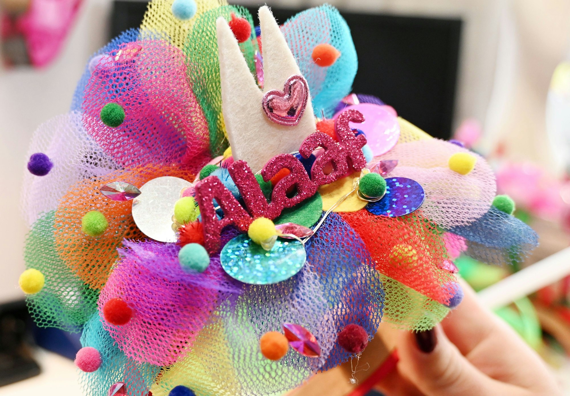 Eine Hand hält einen Tüll-Reif mit Filzdom und Glitzerschriftzug Alaaf.