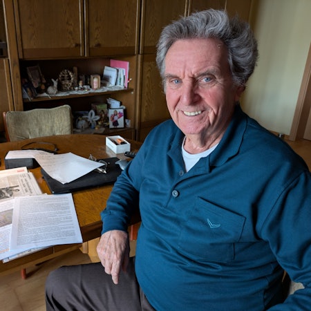 André Heinrichs sitzt am heimischen Wohnzimmertisch und lächelt in die Kamera.