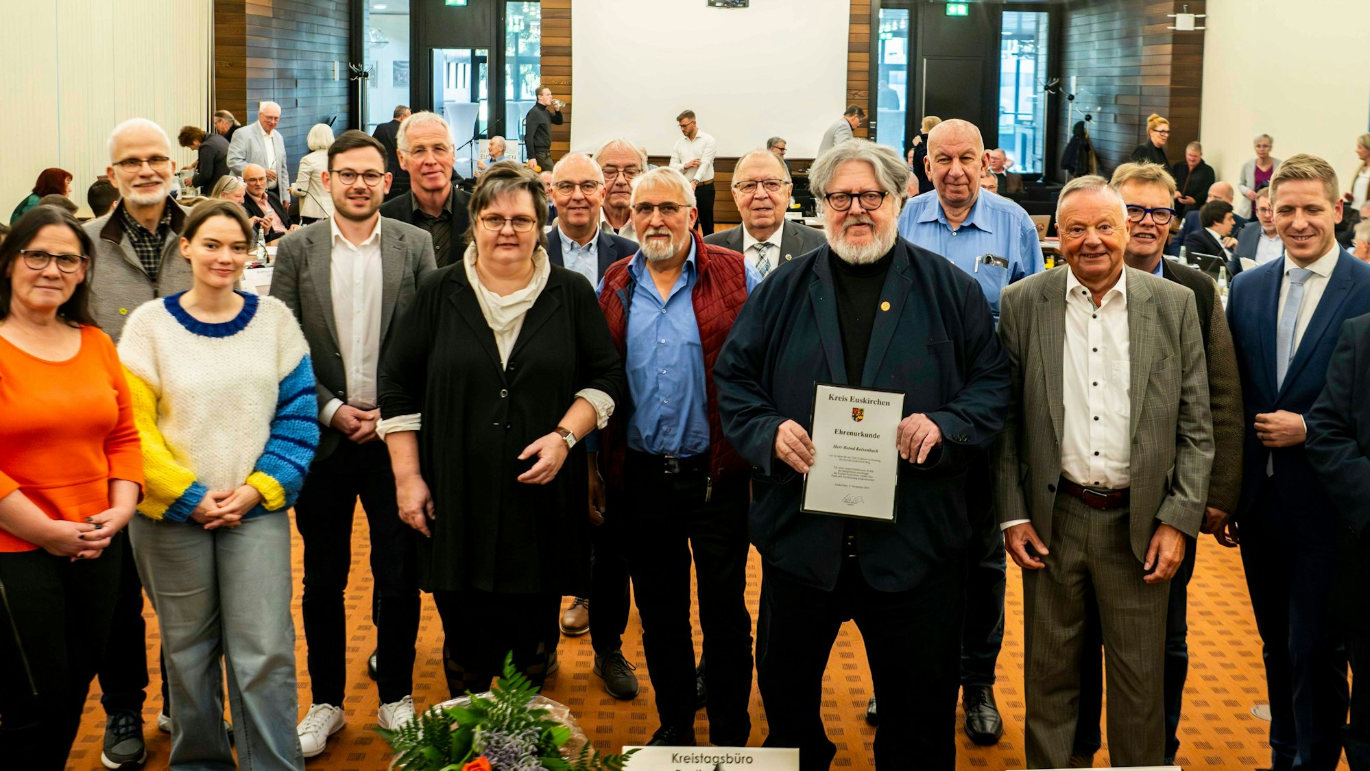 Einige Männer und Frauen stehen zu einem Gruppenfoto im Sitzungssaal des Kreishauses in Euskirchen zusammen.