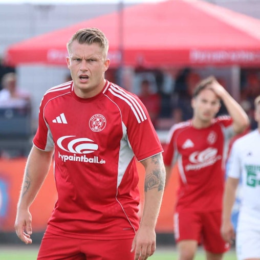 Marvin Iskra schaut konzentriert. Im Hintergrund fährt sich ein Mitspieler mit der Hand durchs Haar.