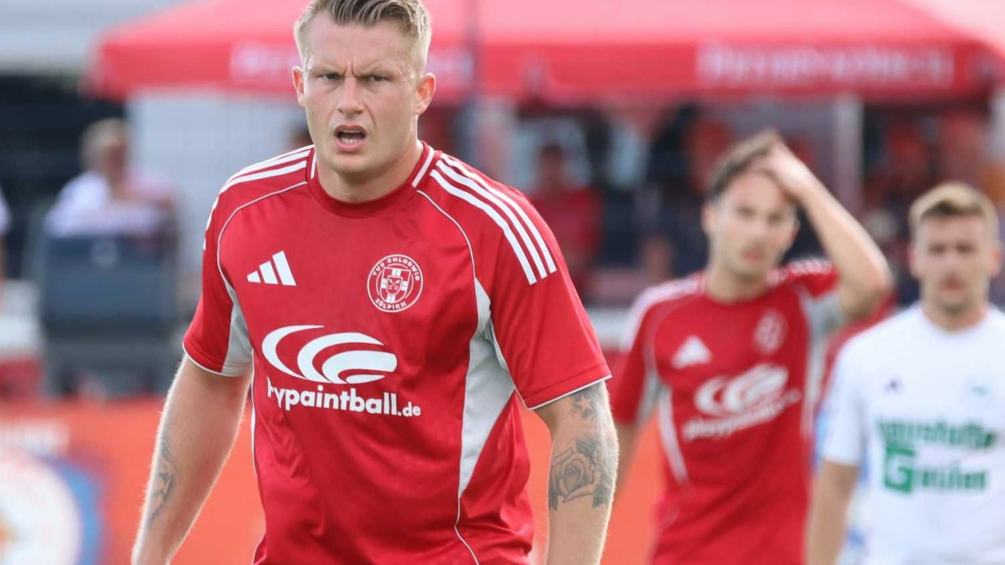 Marvin Iskra schaut konzentriert. Im Hintergrund fährt sich ein Mitspieler mit der Hand durchs Haar.