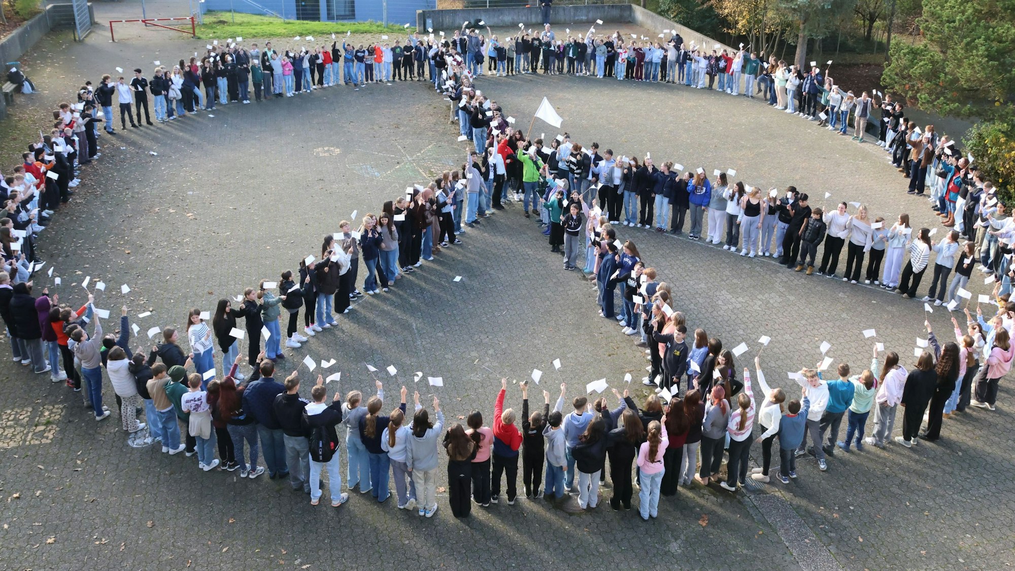 Auf einem der Schulhöfe des Schulzentrums in Waldbröl formen rund 250 Kinder und Jugendliche von der städtischen Gesamtschule ein riesiges „Peace“-Zeichen.