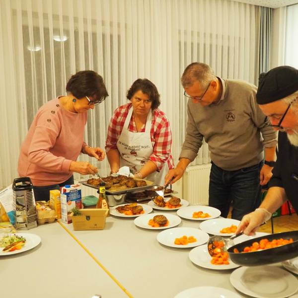 Zwei Männer und zwei Frauen füllen Essen auf Teller.