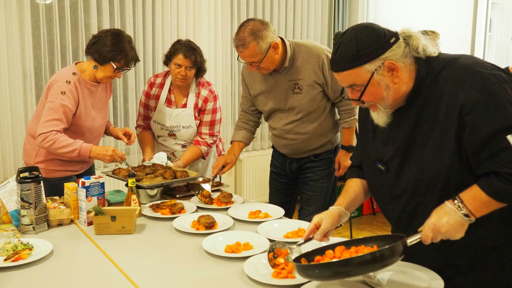 Zwei Männer und zwei Frauen füllen Essen auf Teller.