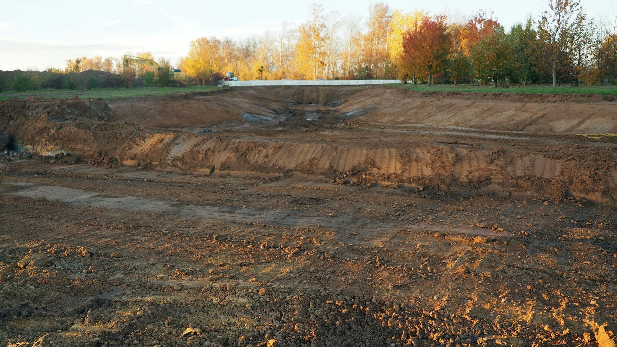 Im Vordergrund befindet sich der ausgehobene Graben, im Hintergrund stehen Bäume.