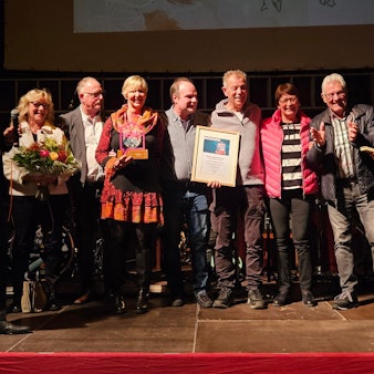 Zu sehen ist eine Gruppe von Menschen bei einer Preisverleihung auf einer Bühne.