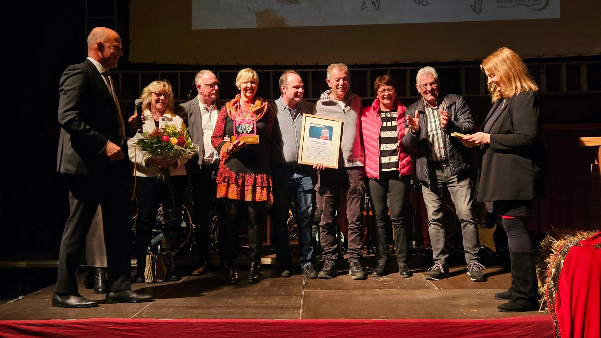 Zu sehen ist eine Gruppe von Menschen bei einer Preisverleihung auf einer Bühne.