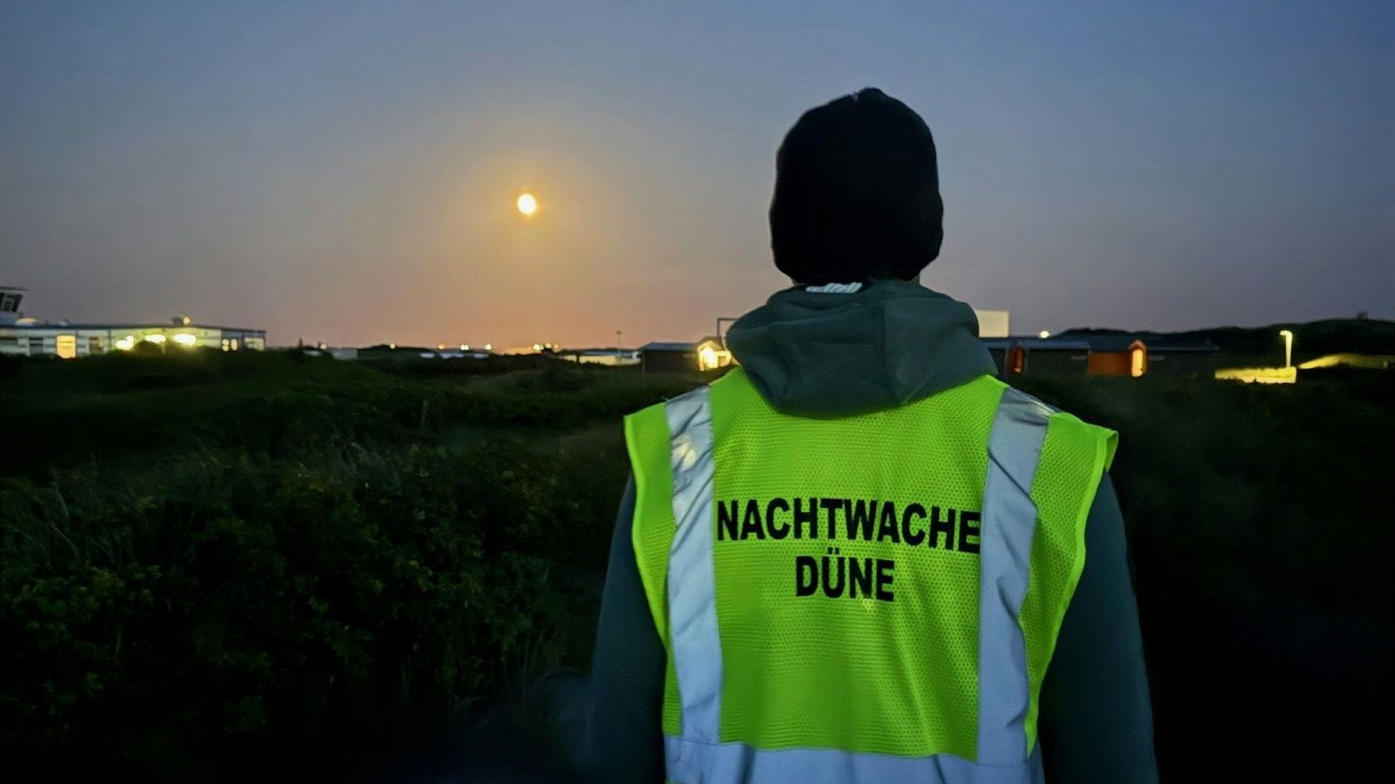 Ein Mann mit Weste, die die Aufschrift "Nachtwache Düne" trägt.
