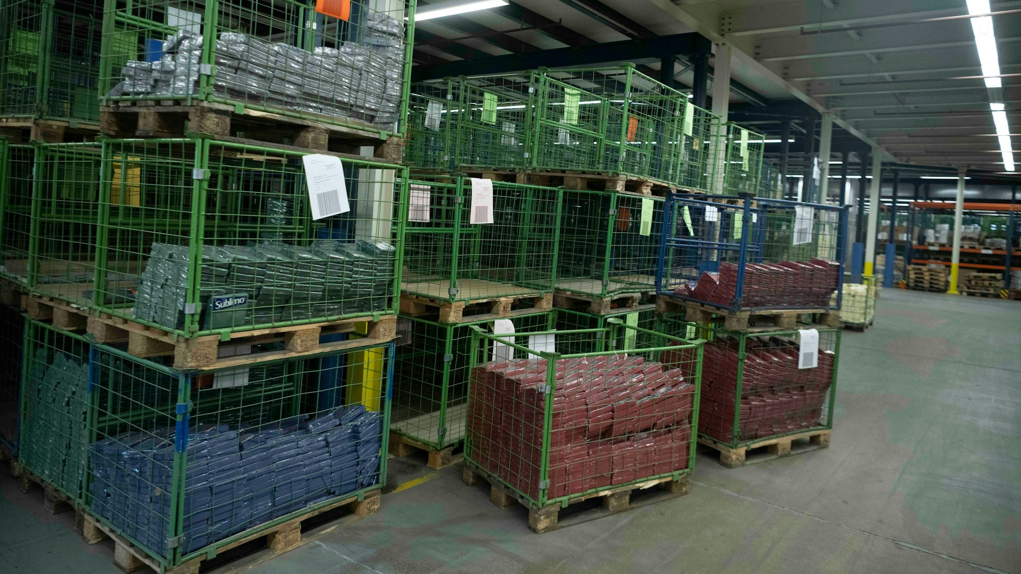 Das Bild zeigt einige grüne Metallkörbe, die entweder leer sind oder in denen einige verpackte Servietten liegen.