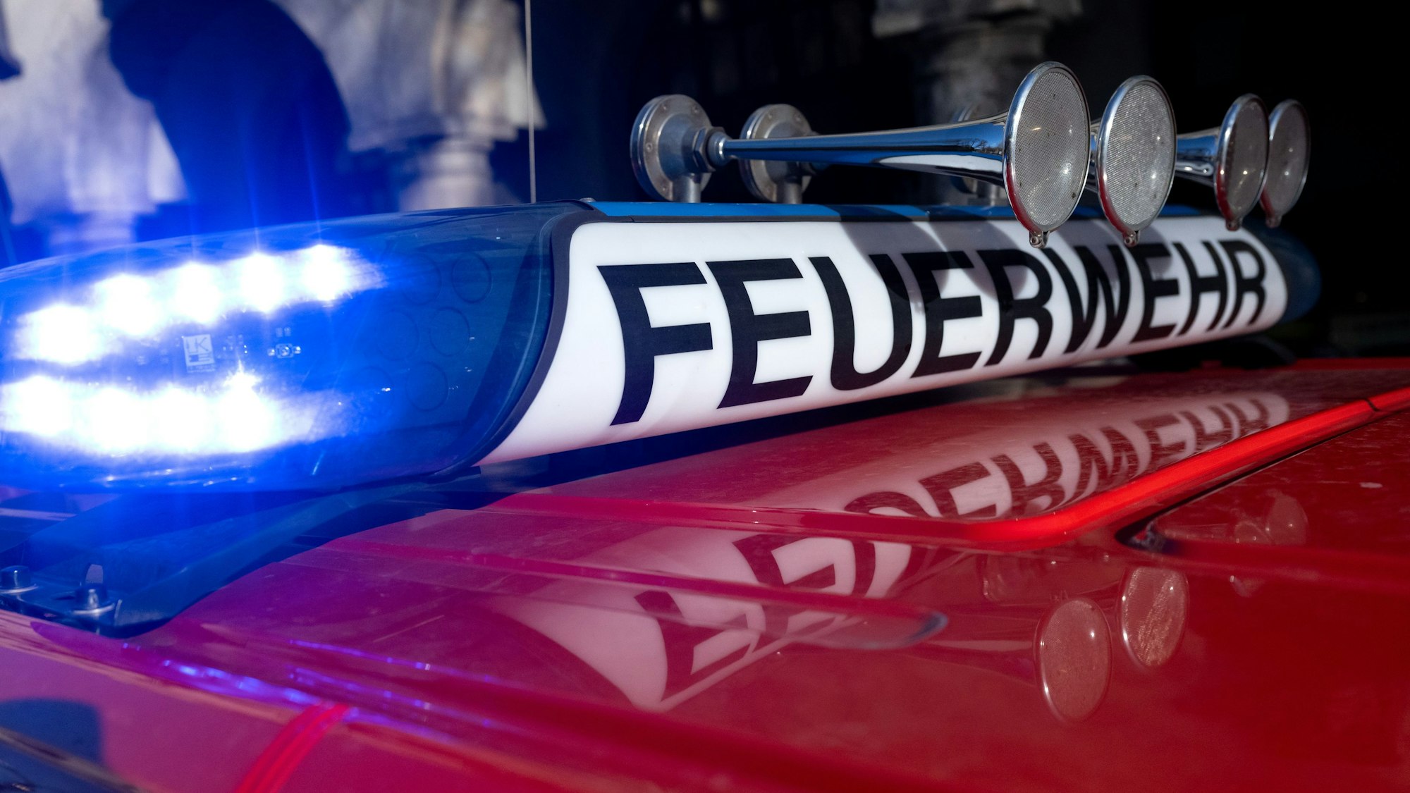 Das Bild zeigt ein Einsatzfahrzeug der Feuerwehr mit eingeschaltetem Blaulicht.