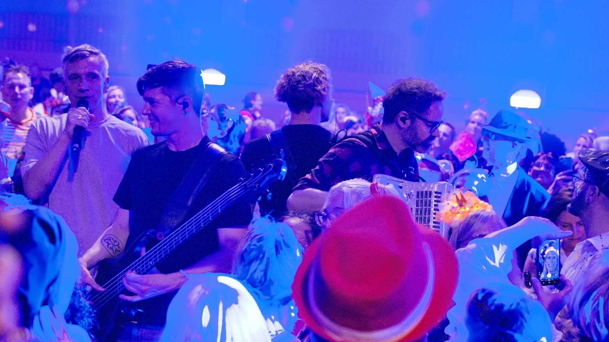 Die Musiker stehen mit ihren Instrumenten inmitten von kostümierten Menschen.