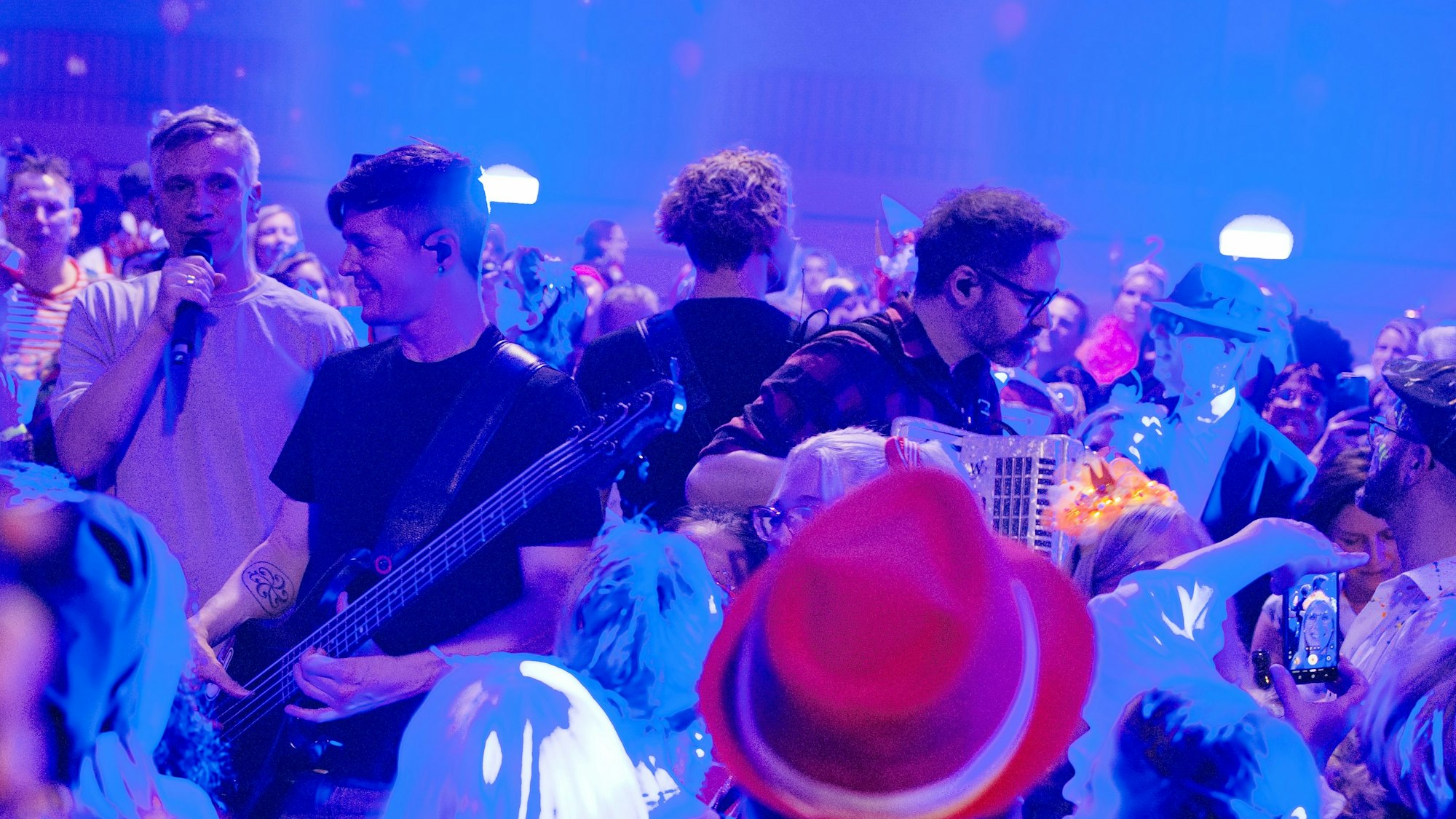 Die Musiker stehen mit ihren Instrumenten inmitten von kostümierten Menschen.