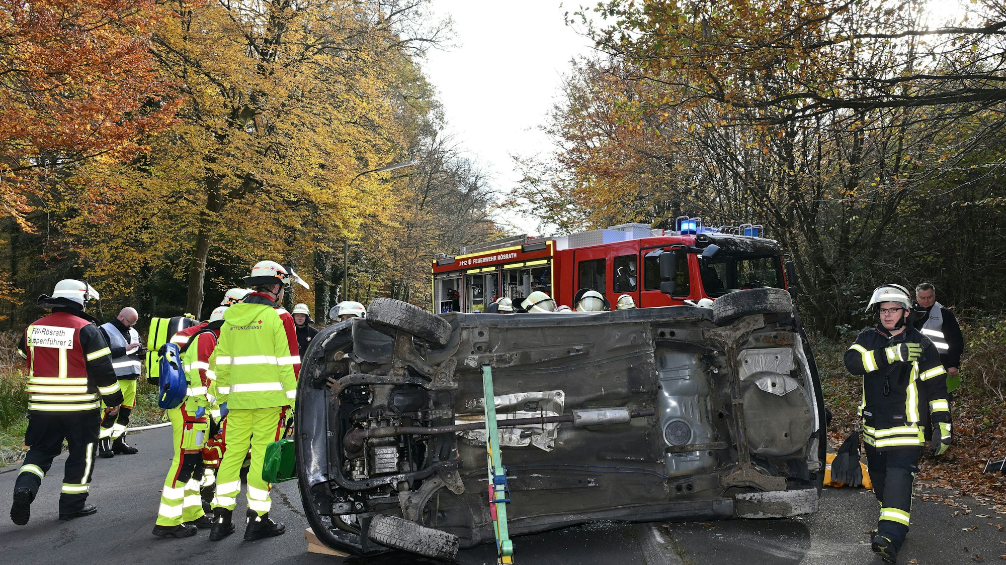 Ein Auto liegt auf der Seite auf der Straße, darum herum Feuerwehrleute.