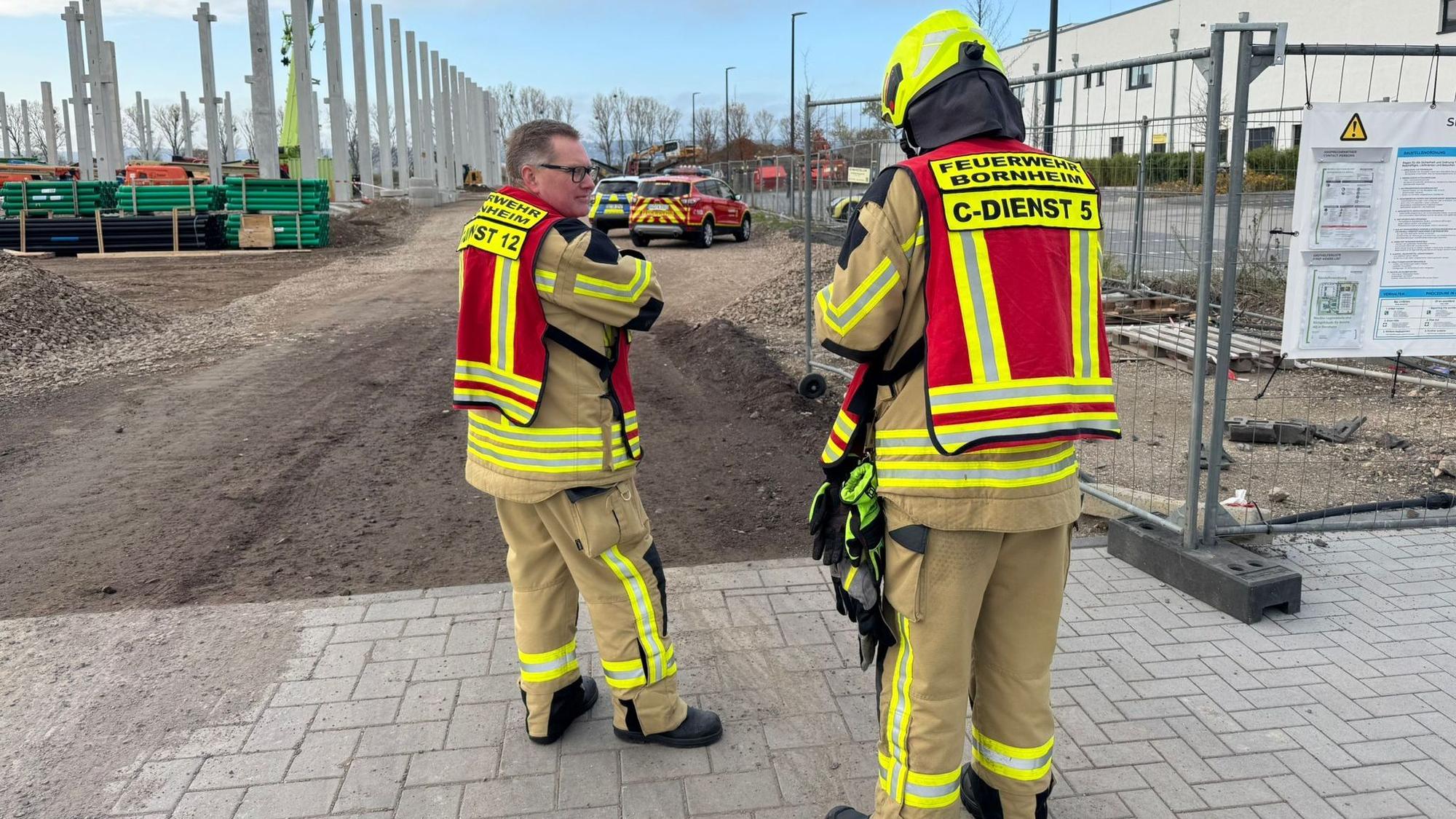 Feuerwehrmänner stehen vor der Baustelle.