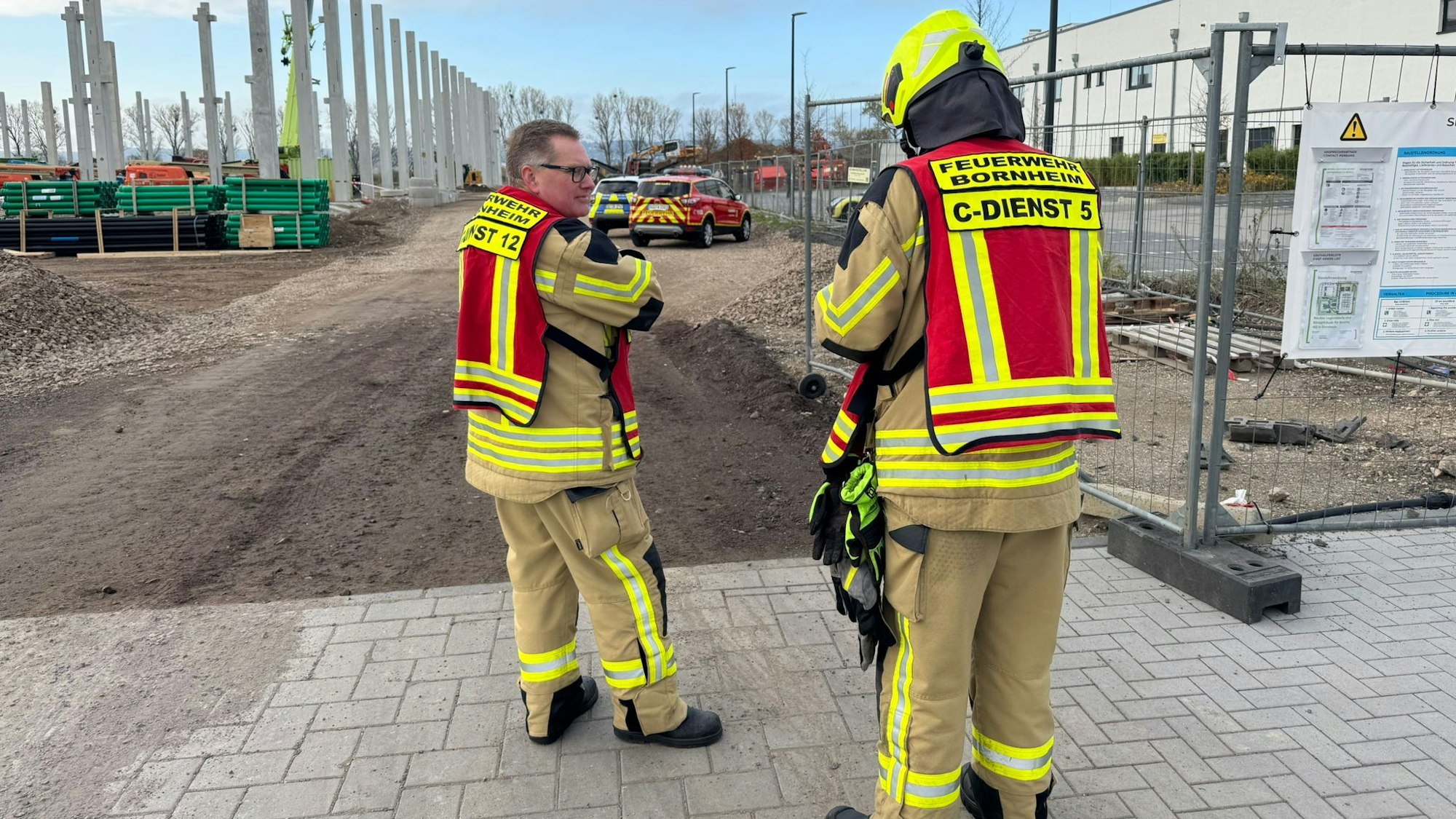 Feuerwehrmänner stehen vor der Baustelle.