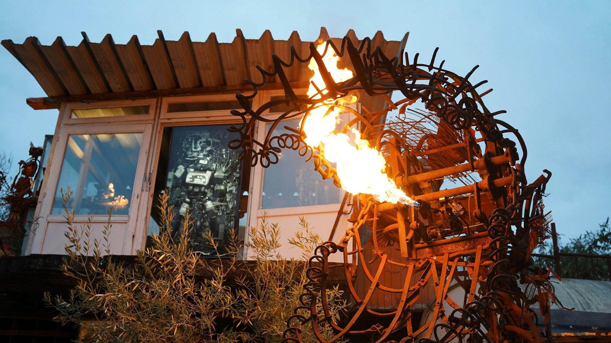 Zu sehen sind Flammen, die aus einer Metallskulptur schießen.