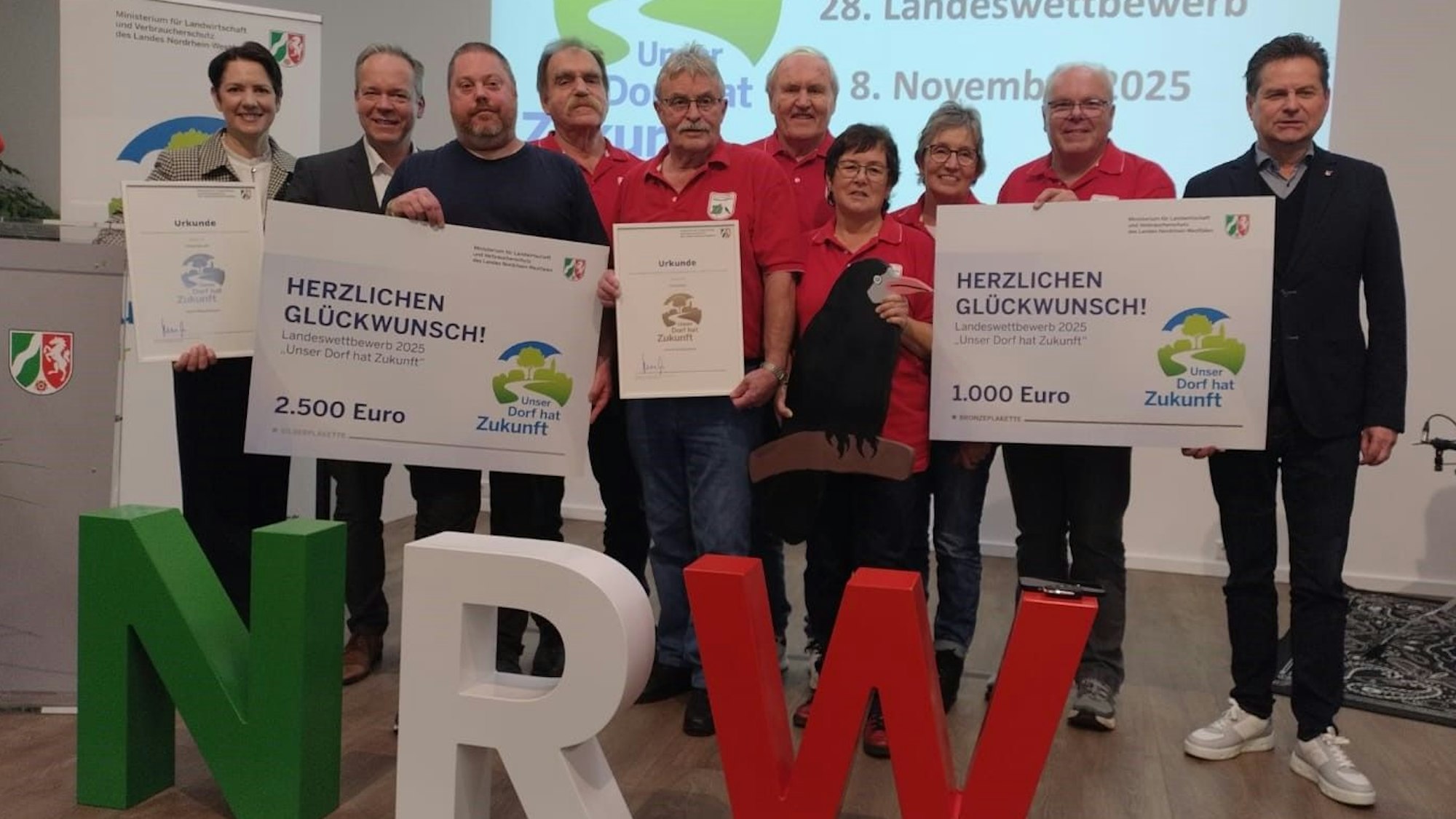 Das Bild zeigt die Abordnungen aus Oberwiehl (in rot) und Hülsenbusch mit der NRW-Ministerin Silke Gorißen (links), Oberbergs Landrat Klaus Grootens (Zweiter von links) und Wiehls Bürgermeister Ulrich Stücker (rechts). Auf dem Bild fehlt Heike Brand.