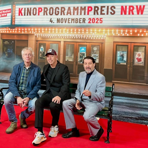 Das Foto zeigt die Vertreter der Preisträger auf einer Bank vor einer Kinokulisse.