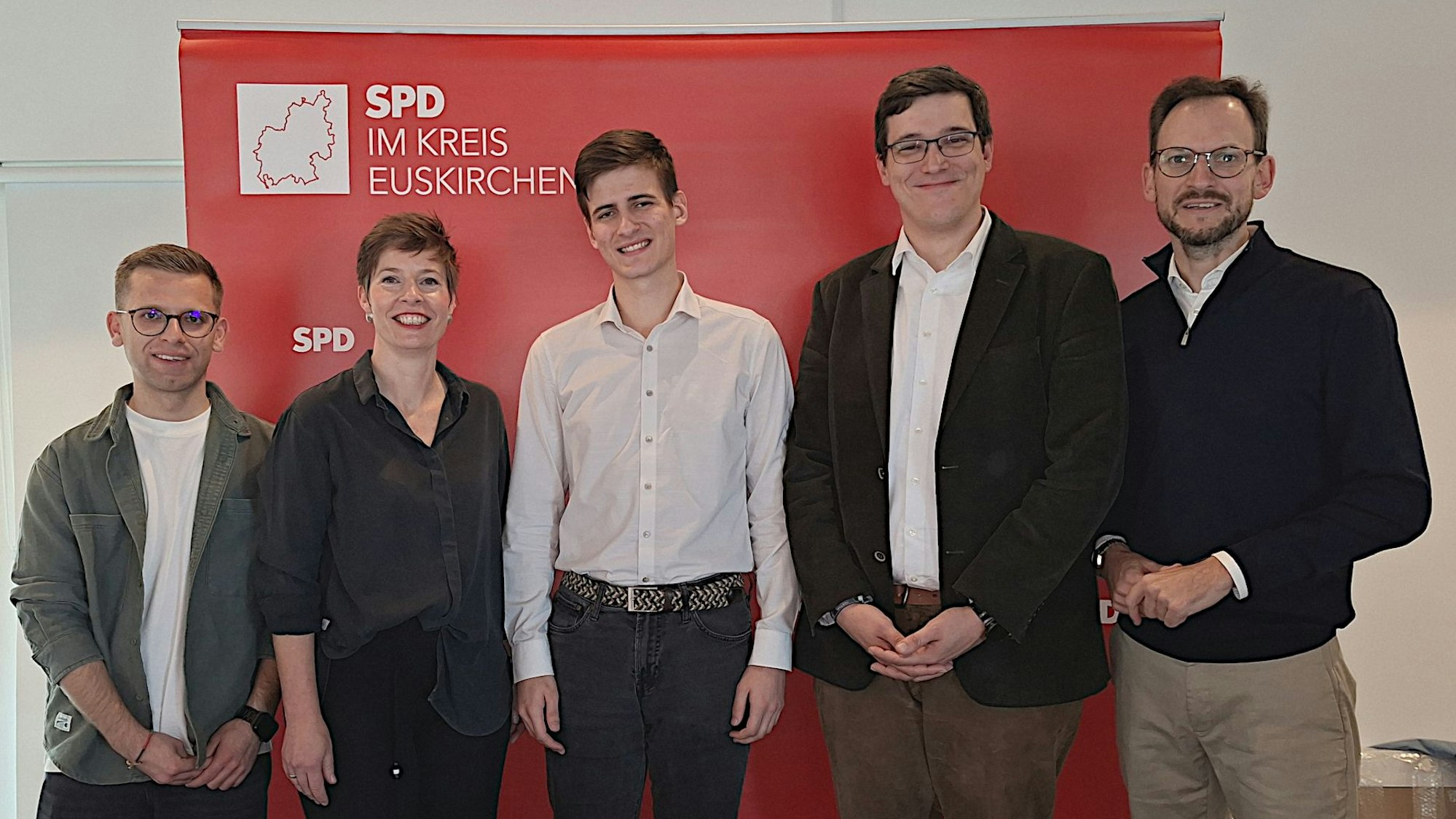 Die Genannten, die nebeneinander stehen, lächeln in die Kamera.