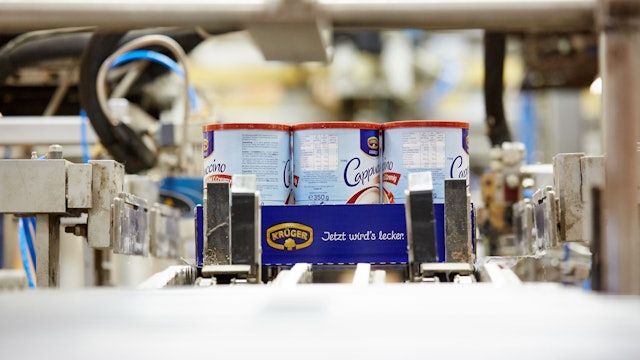 Drei Dosen mit Krüger-Cappuccino auf einem Produktionsband.