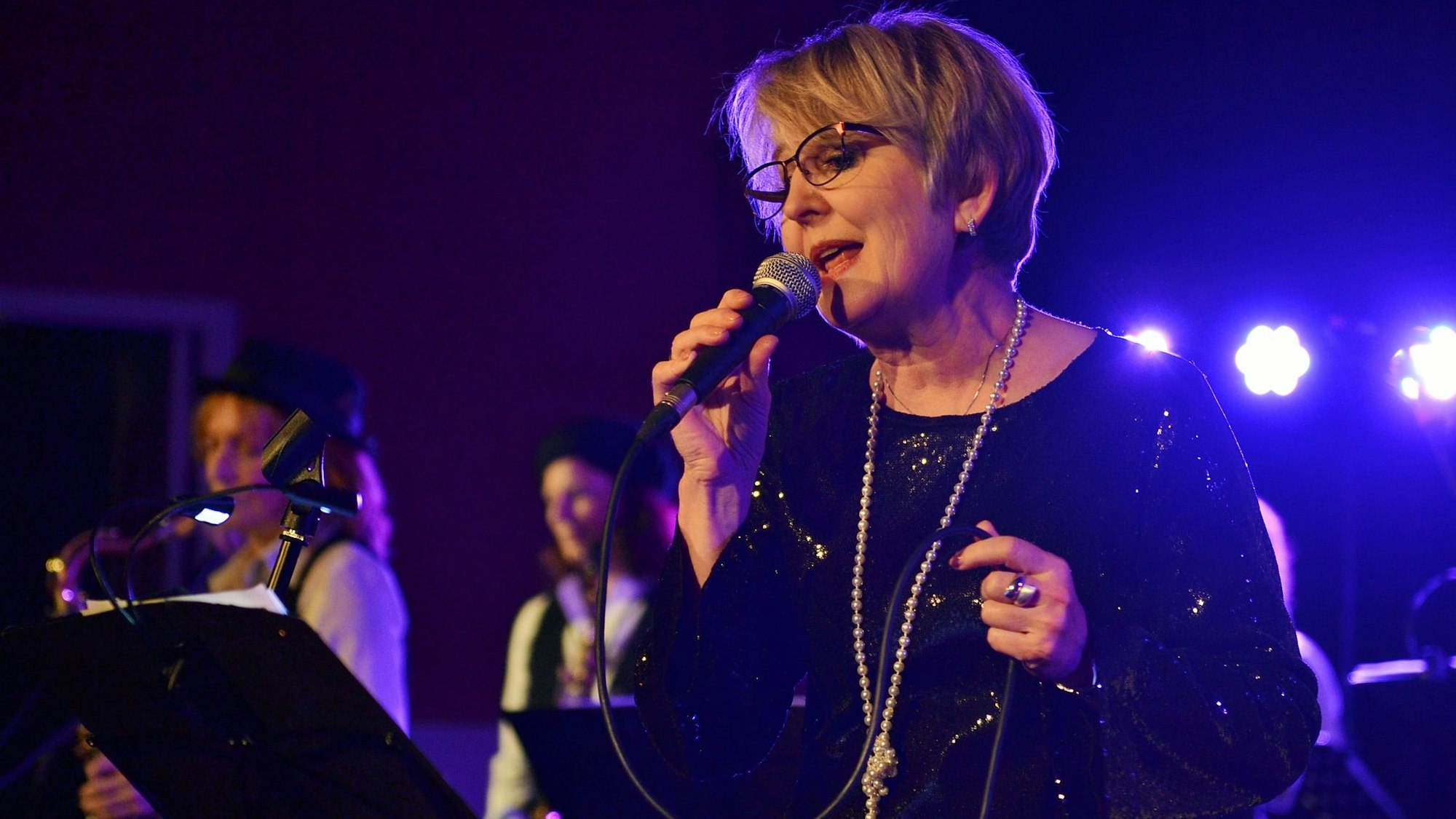 Im Vordergrund ist die Sängerin zu sehen, dahinter leicht unscharf Instrumentalisten.