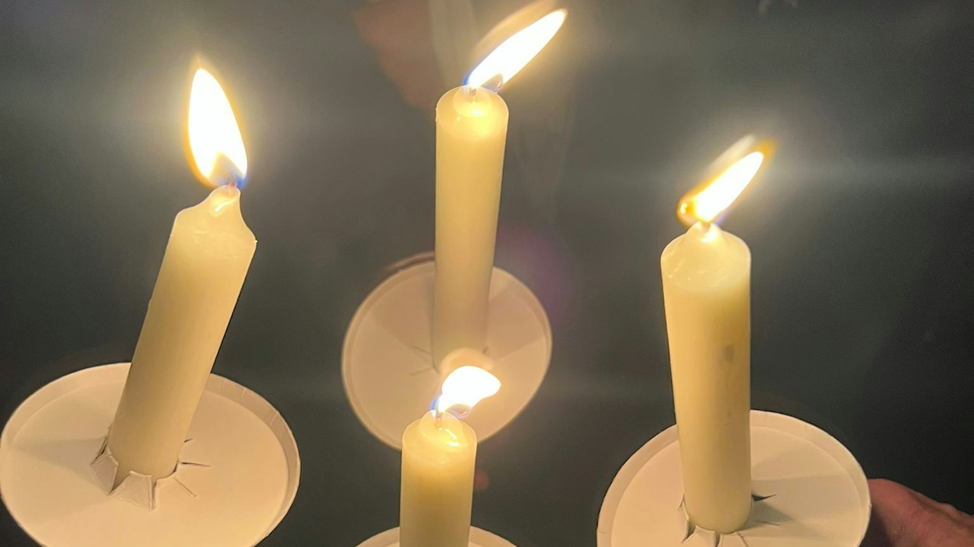 Das Bild zeigt vier brennende, weiße Stabkerzen.