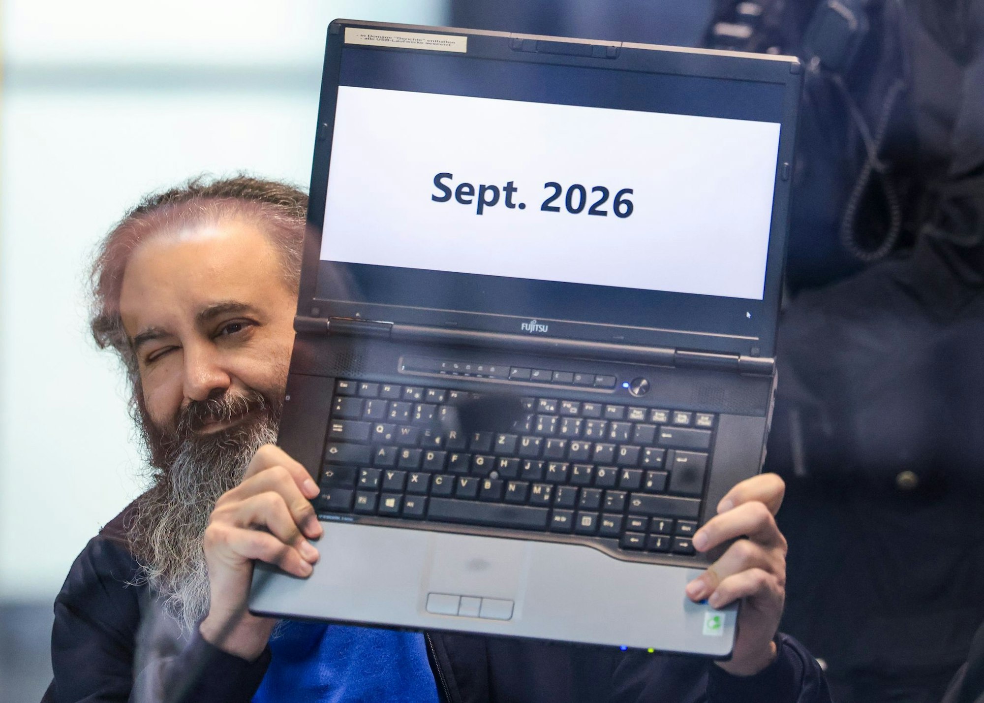 Der Angeklagte Taleb al-Abdulmohsen hält zu Prozessbeginn seinen Laptop mit der Aufschrift „Sept. 2026“ hoch.