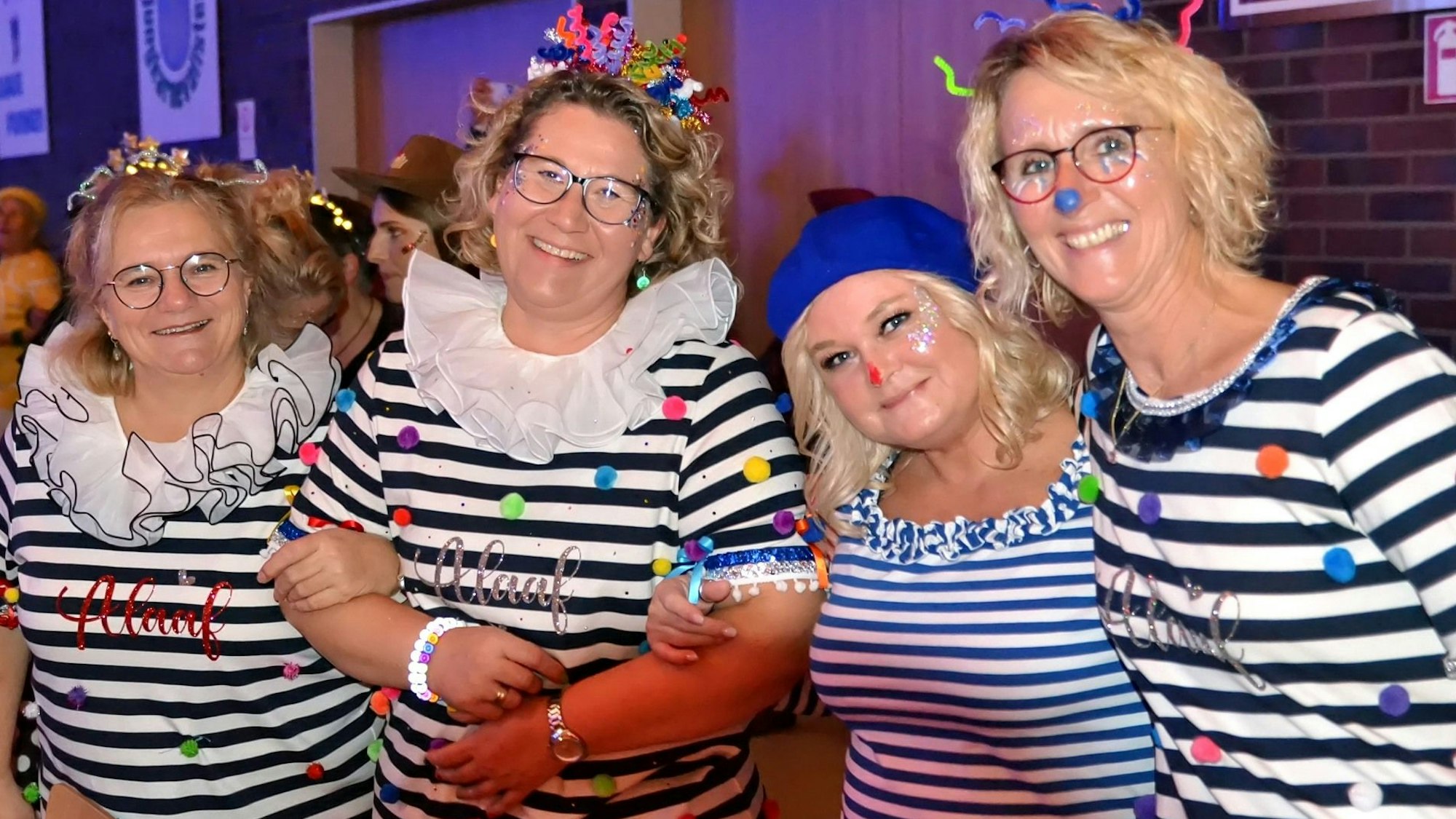 Vier Besucherinnen in gestreiften Kostümen schunkeln.