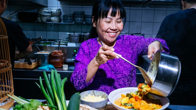 Thu Khue Pham füllt veganes Curry auf einen Teller.