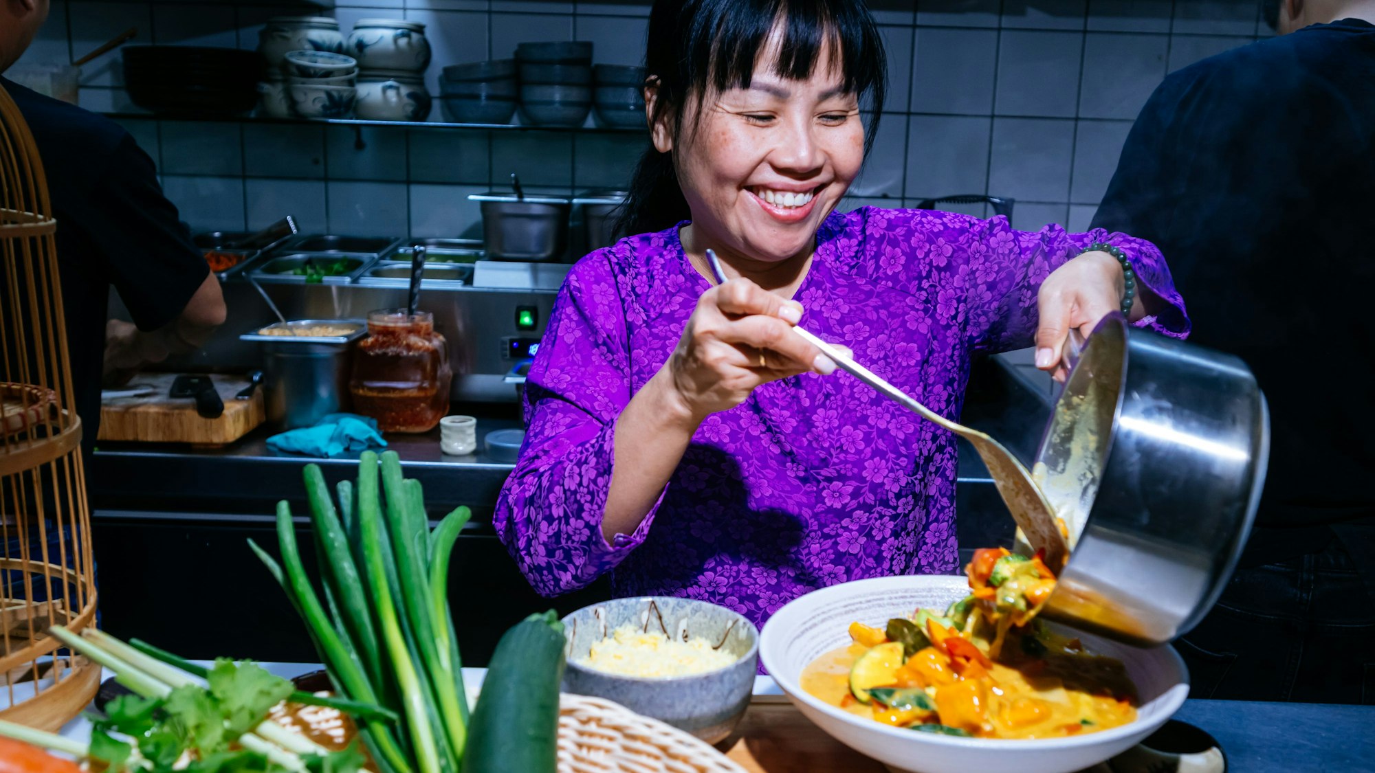 Thu Khue Pham füllt veganes Curry auf einen Teller.