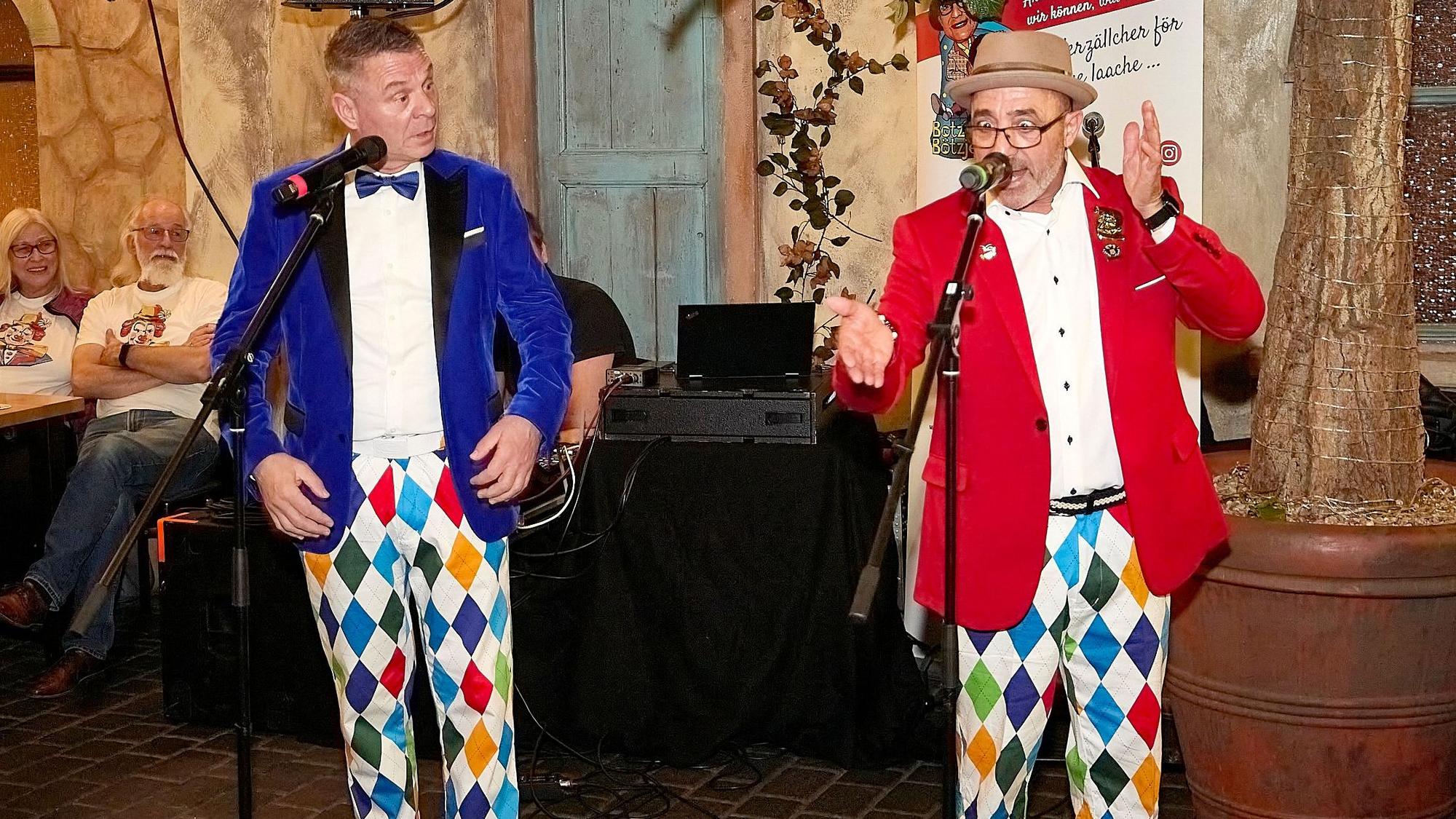 Das Redner-Duo Botz und Bötzje steht in bunten Kostümen an den Mikrofonen.