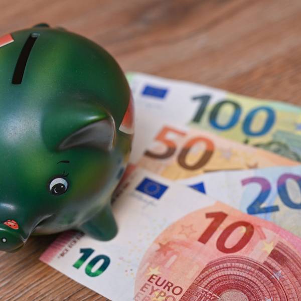 Ein Sparschwein steht auf einem Tisch neben Eurobanknoten. (Symbolbild)