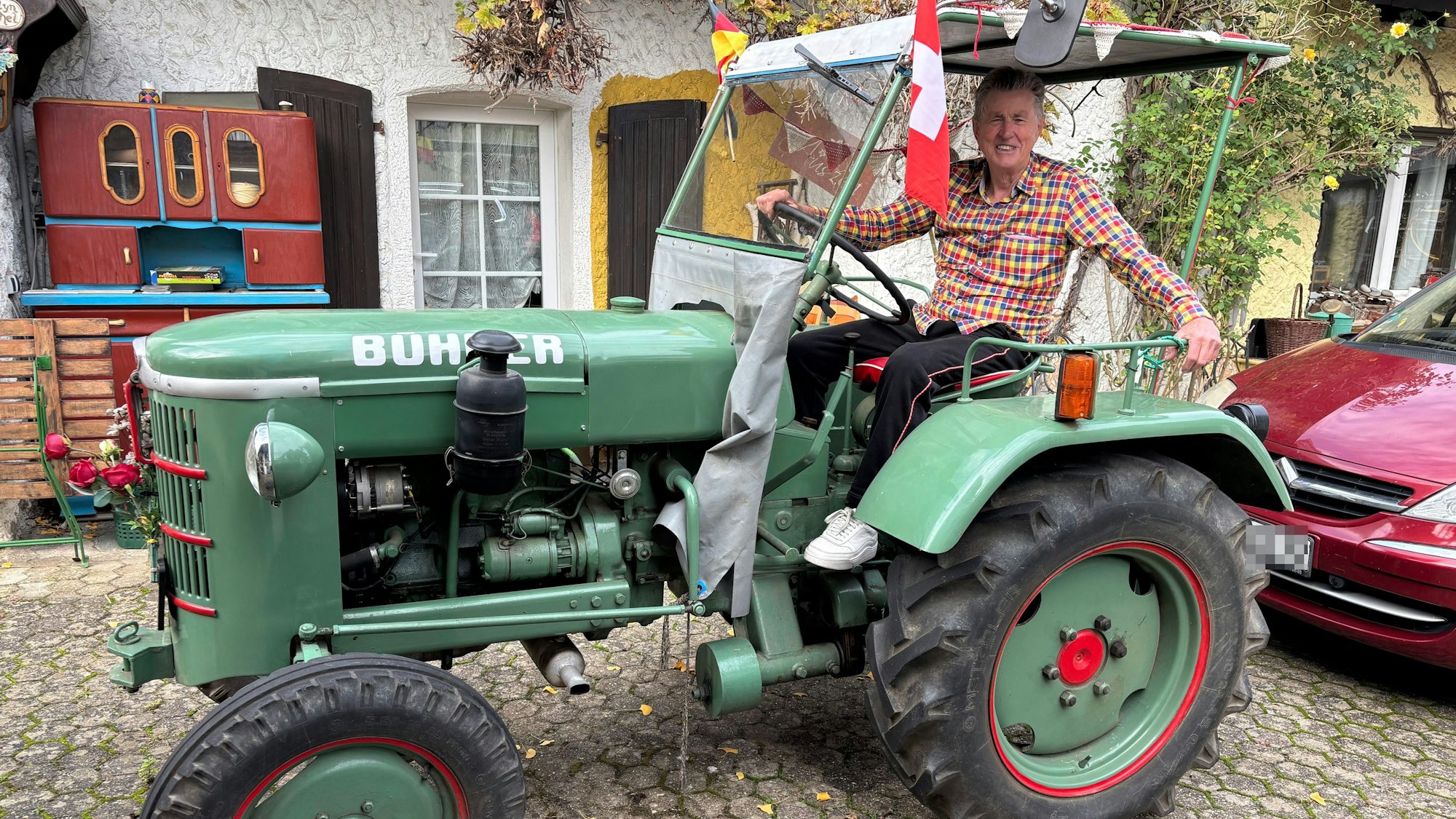 Günter Klein trägt ein kariertes Hemd und sitzt in einem Traktor.
